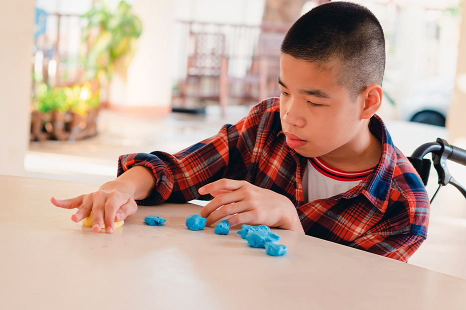 A young boy plays with blue blocks on a table, highlighting the importance of physical therapy for children with learning disabilities.
