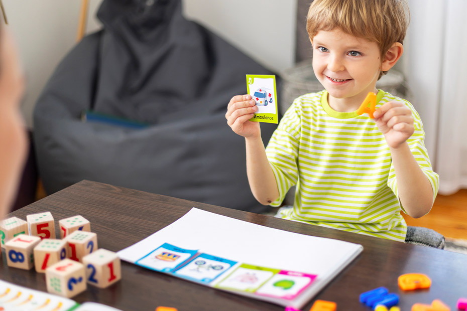 A young child focused on playing cards, highlighting the role of play in enhancing cognitive skills through therapy.