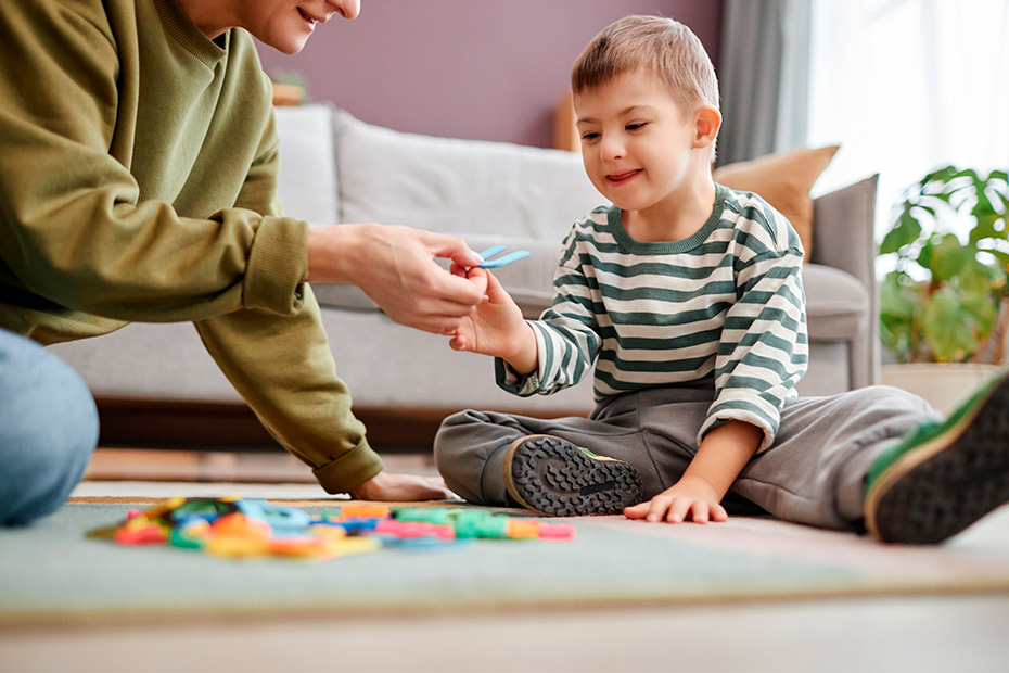 A man and a child engaged in play with toys on the floor, promoting learning and development through fun activities.