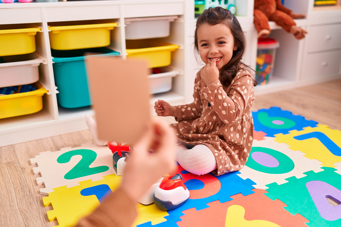 A woman engages in playful activities with a child in a classroom setting, focusing on speech therapy games.