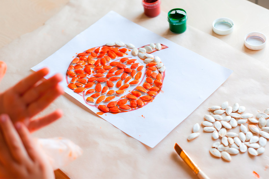A child's hands grasp a pumpkin resting on paper, showcasing a creative activity for home-based occupational therapy.