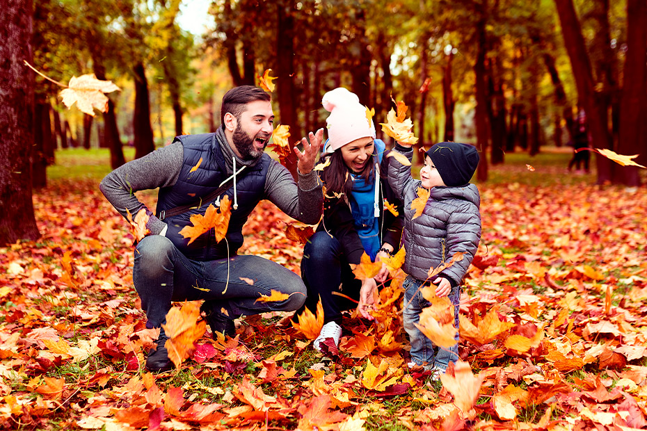 A family enjoying playful moments in vibrant autumn leaves, highlighting activities for occupational therapy at home.