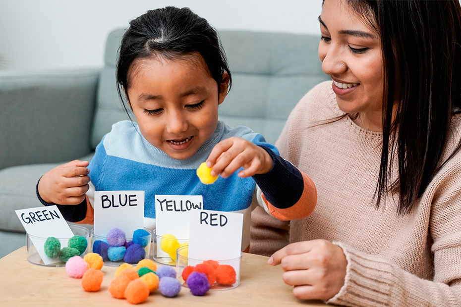  A woman and child engaged in play with vibrant balls, highlighting the positive impact of occupational therapy on autistic children.