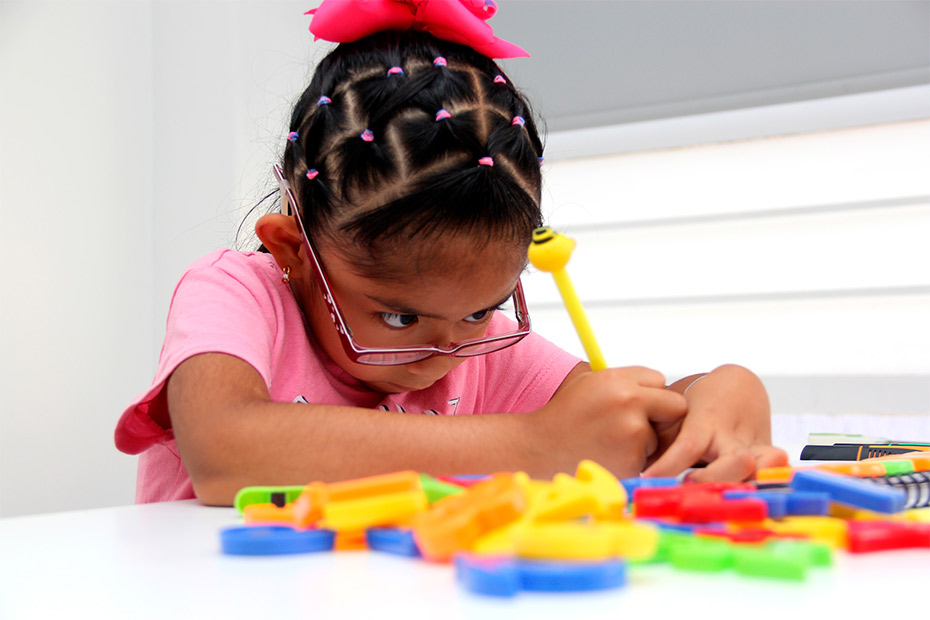 A young girl focuses intently on assembling a colorful puzzle, showcasing her engagement in a therapeutic activity.