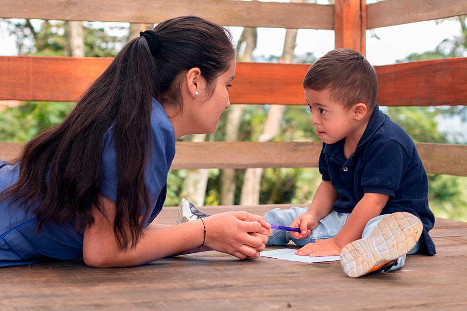 A woman and a child seated on a wooden floor, exploring signs that suggest the child might benefit from occupational therapy.