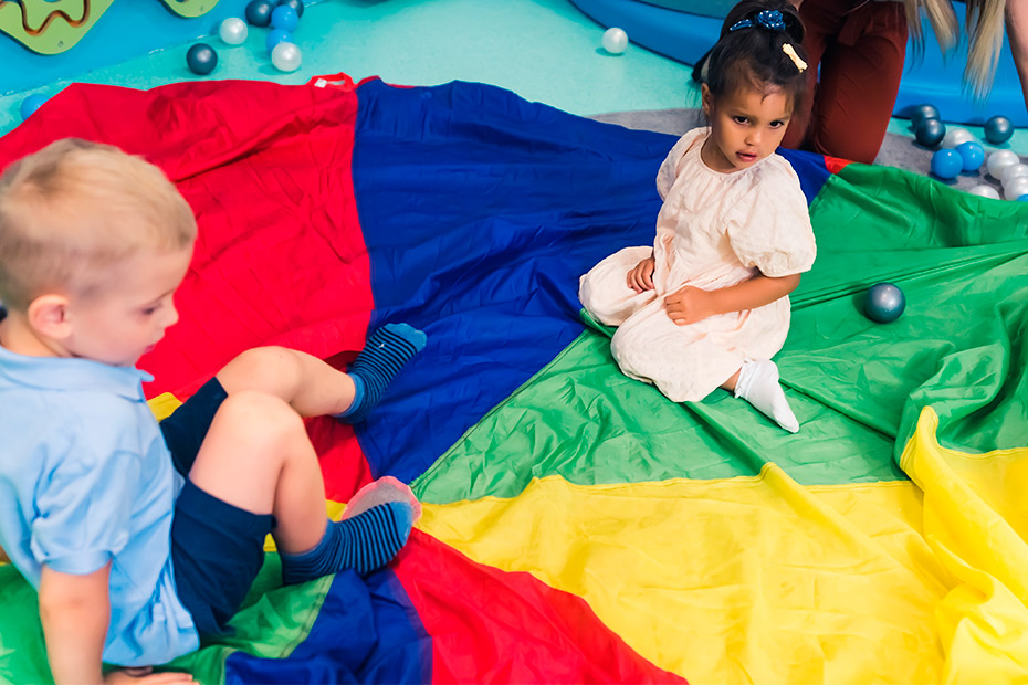 A vibrant playroom scene with children playing on a colorful blanket, showcasing joyful interactions and imaginative play.