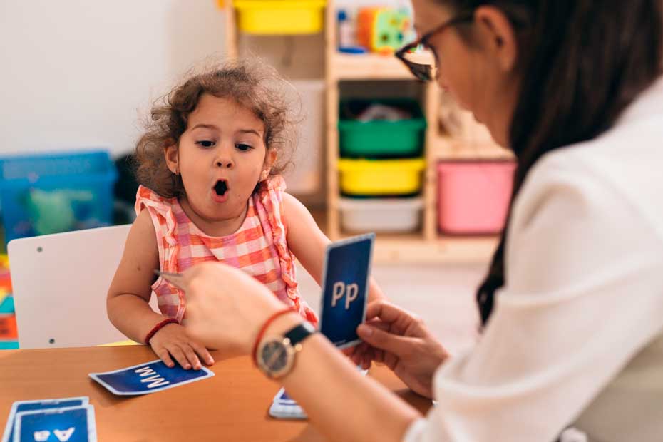 psychologist having speech support session with young girl in kindergarden