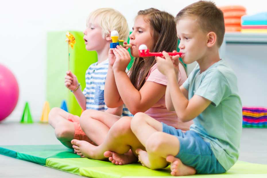 Group of young children making breathing exercises during physical therapy session. Kids in group physiotherapy.