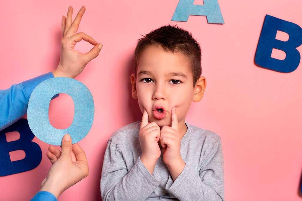 Portrait of a 4 year old boy speech therapy concept on pink background. Correct pronunciation and articulation at preschool age.