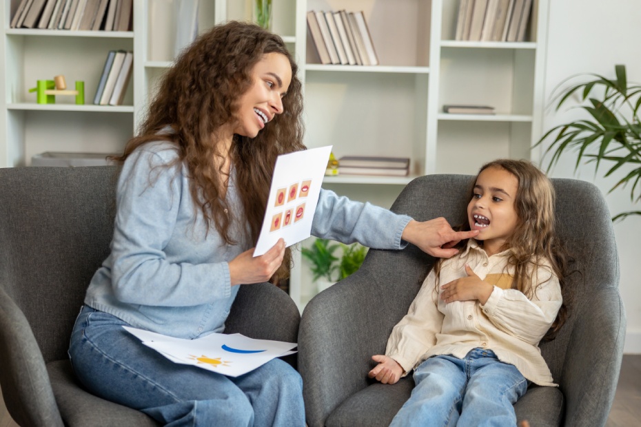 Long-haired cute girl working with a speech therapist and looking attentive
