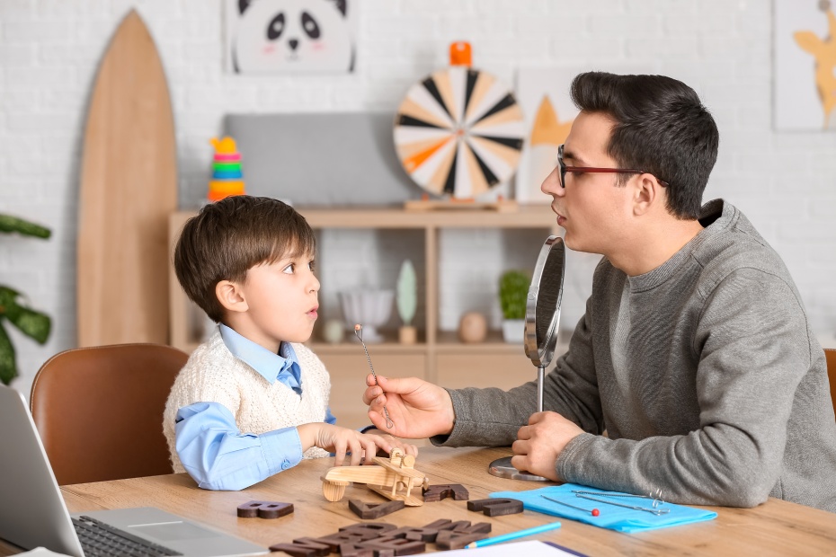 Speech therapist working with little boy in office