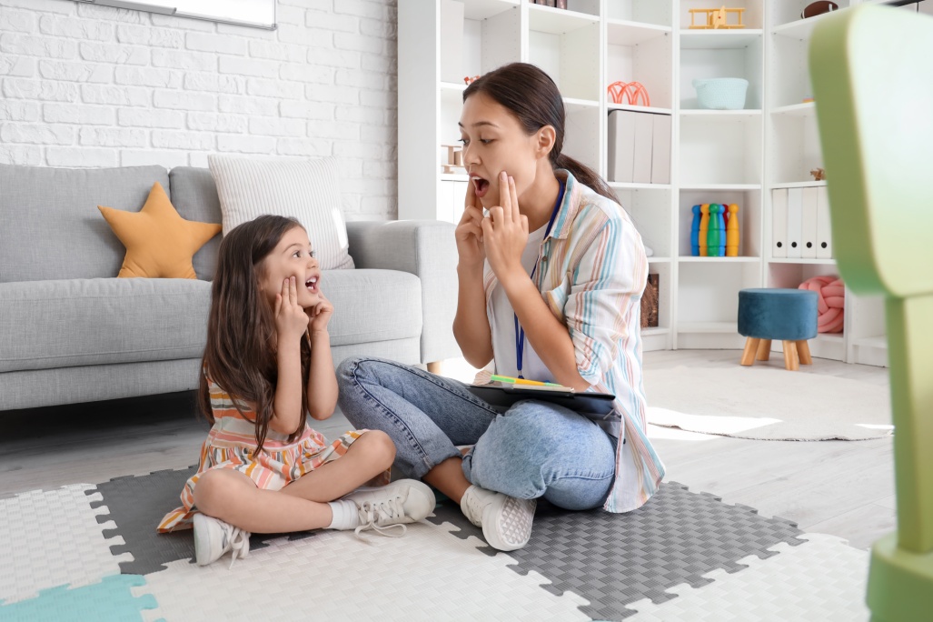 Female Asian speech therapist working with little girl in office